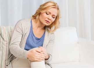 unhappy woman suffering from pain in leg at home