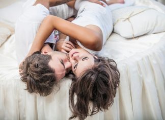 Couple man and woman lay cuddling on the bed at home